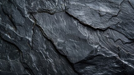 A close up of a rock wall with a dark grey color. The rock wall has a rough texture and he is made of granite