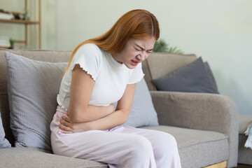 asian woman suffering from stomach ache, undergoing belly pain and discomfort, suffer from...