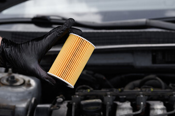 Automotive parts. Auto mechanic holds oil filter for diesel cars in black gloves, close-up. Car service in car service center. Checking technical condition of filter before installation.