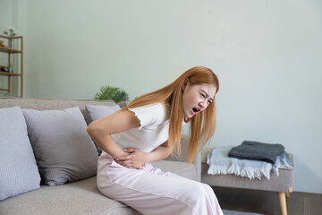 asian woman suffering from stomach ache, undergoing belly pain and discomfort, suffer from...