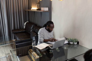 Young African American business man working with laptop and mobile on desk at home. work from home concept