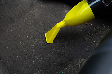 Cleaning floor of car interior from sand and dirt using portable vacuum cleaner. Dry interior cleaning, professional car interior cleaning