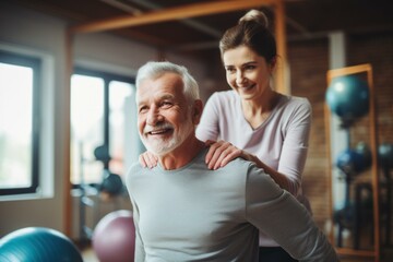 Joyful elderly gentleman with a supportive female personal trainer in a fitness center