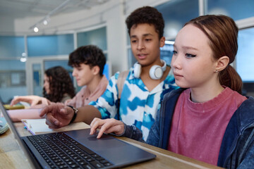 Portrait of Asian teenage girl using laptop computer during tech class in modern school copy space