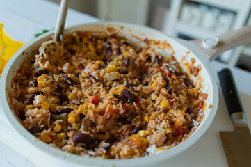 Healthy rice dish with ham, kidney beans, corn, peppers, onions, tomatoes and herbs. Low fat and high protein dinner or luch in a frying pan