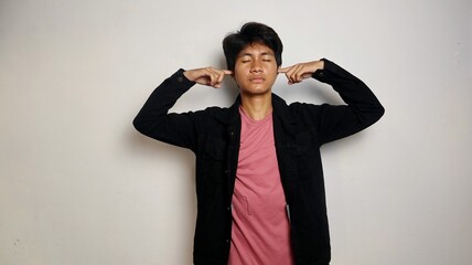 Young Asian man posing covering his ears with his hands