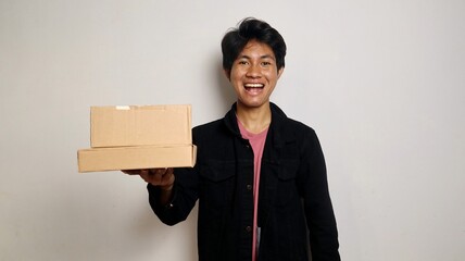 excited young asian man holding parcel box package. Delivery courier and shipping service concept