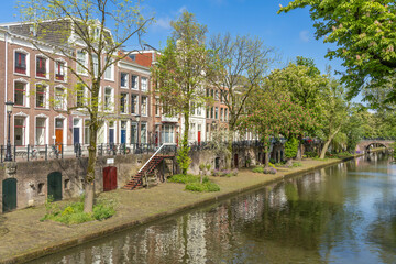 Obraz premium Oudegracht canal seen from a bridge. wooden stairs from the wharf to the street. traditional brick stone houses along the street with bicycles.