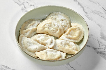Sweet Polish pierogi sprinkled with powdered sugar in rustic bowl