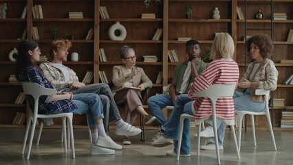 Diverse adults engaged in a group therapy session in a cozy room with bookshelves