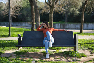 Young, beautiful woman in orange T-shirt and jeans, distracted and absorbed in her thoughts,...