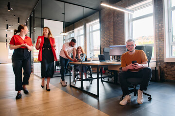 A diverse group of business professionals collaborates in a modern startup coworking center, utilizing a mix of paper-based and technological tools such as mobile phones and computers 