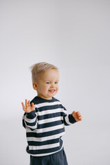 Cute smiling toddler boy standing in room against of white background.