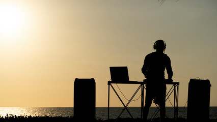 DJ plays music during sunset on the beach