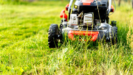 Obraz premium Lawn mower on a green flat lawn on a sunny day