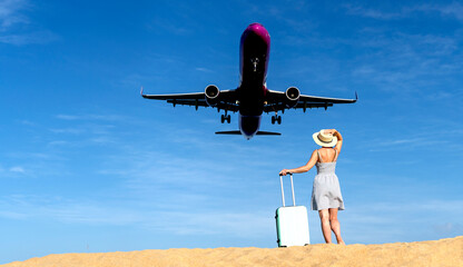 A girl on the beach with a suitcase sees off or meets a plane