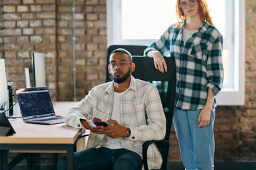 A diverse group of young business individuals congregates in a modern startup coworking center,...