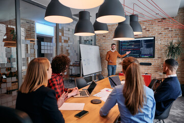 In a corporate setting businessman leads a meeting, passionately presenting a business plan to his attentive team, fostering collaboration and strategic thinking