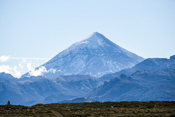Fototapeta premium Lanin volcano surrounded by clouds, clear summit in sight and ice glaciers, between Argentina and Chile, Lanin National Park