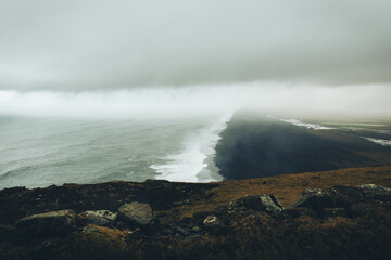 Picturesque view dramatic popular panorama to endless ocean black volcanic sand beach from Dyrholaey Cape, Vik, South Iceland in overcast day. Vestmannaeyjar islands