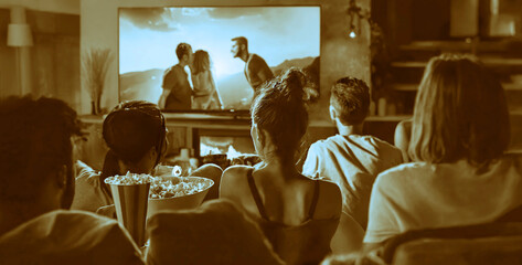 Group of friends. young people watching movie, soccer match at home in evening. Group of students watching TV set. Friends Sitting At Home. Relaxing on a Couch. Apartment with Friends Eating Snacks