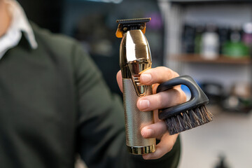 Trimmer and brush in the hand of barber. 