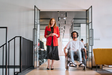 A business leader with her colleague, an African-American businessman who is a disabled person,...