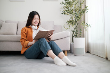Fototapeta premium Relaxed young woman reading book in living room, spending leisure time at home.