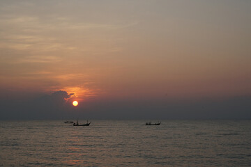 Fototapeta premium The perspective of the fishing boat in the sea with a sunrise background