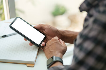 Close up view of man hands holding smart phone over working desk. Blank screen for your advertise design.