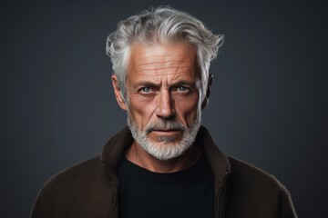 Fototapeta premium Portrait of a distinguished mature man with a commanding gaze against a dark background
