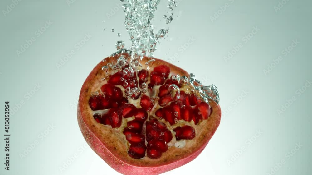 Poster super slow motion of falling pomegranate. splashing into water on grey background. filmed on high sp
