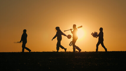 A group of cheerful farmers with equipment walks through a field at sunset