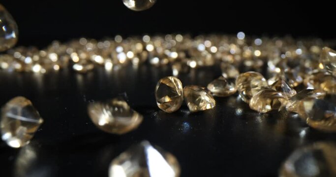 Falling golden yellow diamonds on black background. Valuation and extraction of precious stones
