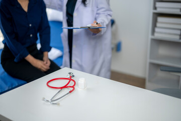 A woman is sitting in a hospital room with a doctor standing next to her