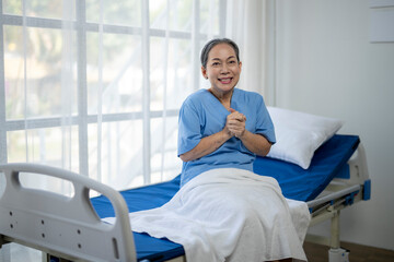 A woman in a blue hospital gown is sitting on a hospital bed