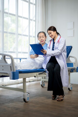 A woman in a white coat is sitting next to a woman in a hospital bed