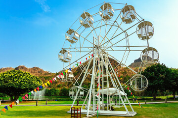 Beautiful scenic with white ferris wheel decorated with lights and small flags for fun and...