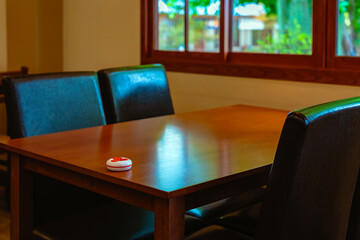 Pager device for ordering food on wooden table in restaurant. Wireless restaurant pager caregiver pager wireless call system. Queue paging wireless calling system. Button transmitter calling system.