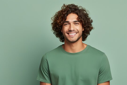A man with curly hair is smiling and wearing a green shirt - Powered by Adobe