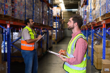 Warehouse worker in safety uniform check the stock order details and goods supplies in the...