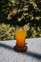 Freshly squeezed orange and tangerine juice with lime in a glass. Iced drink on a tropical background