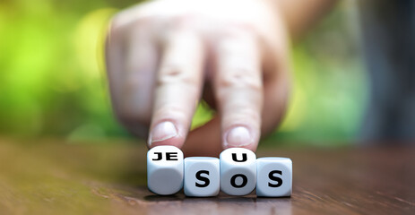 Hand turns dice and changes the expression 'SOS' to 'Jesus'. Symbol that Jesus can help in a crisis.