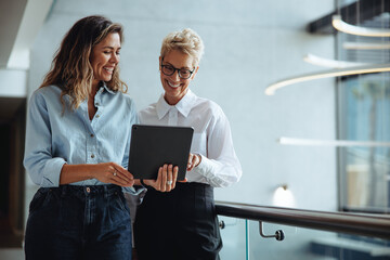 Female executive assistant using a tablet to show her boss a positive business report