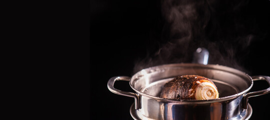 Steamed taro tuber in boiling pot steams up as a chef opens the lid of a pot.