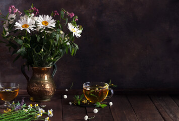 cup of herbal tea and a bouquet of chamomile flowers