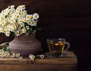 cup of herbal tea and a bouquet of chamomile flowers