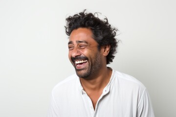 Fototapeta premium Portrait of a happy indian man in his 30s laughing isolated on white background
