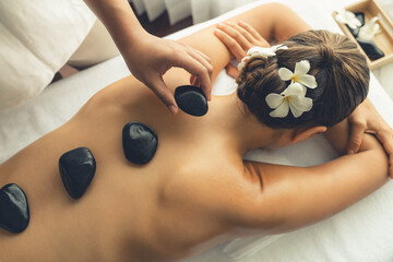 Hot stone massage at spa salon in luxury resort with day light serenity ambient, blissful woman...