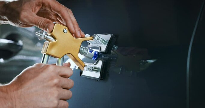 paintless car dent repair tool. man fixing vehicle door with PDR technology